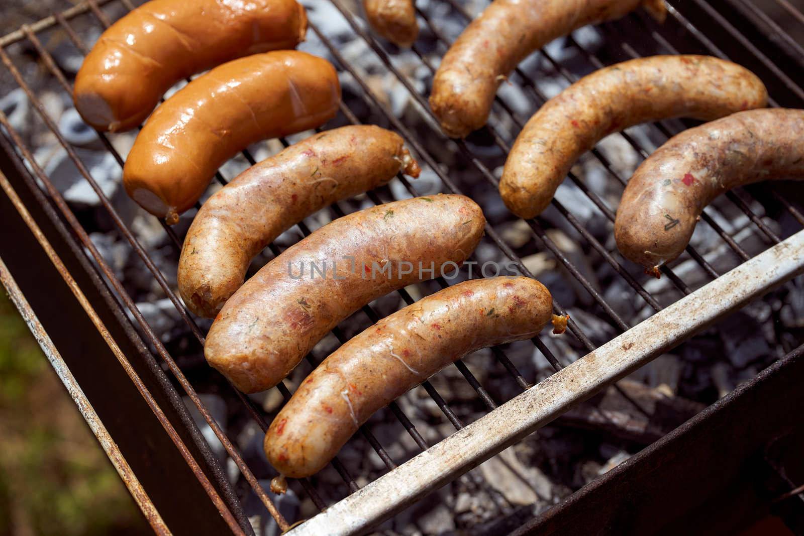 Homemade grilled meat sausages in a white plate on a green background. High quality photo