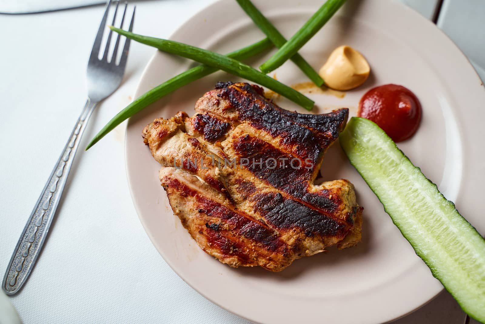 Ready pork steak in a white plate with green onions on a white plate. With copy space. High quality photo