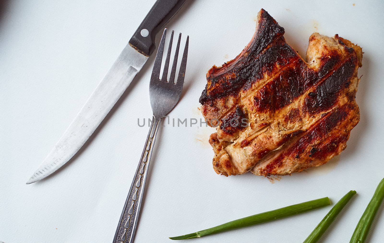 Ready pork steak in a white plate with green onions on a white plate. With copy space. High quality photo