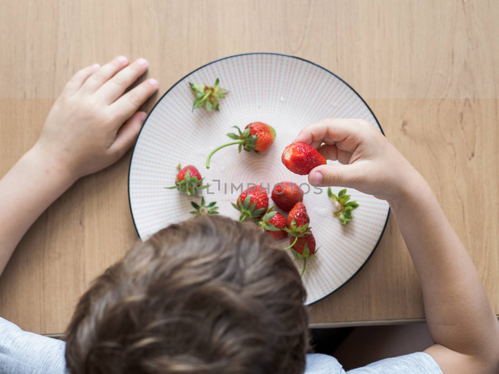 Little boy eats fresh organic strawberry with relish by fascinadora