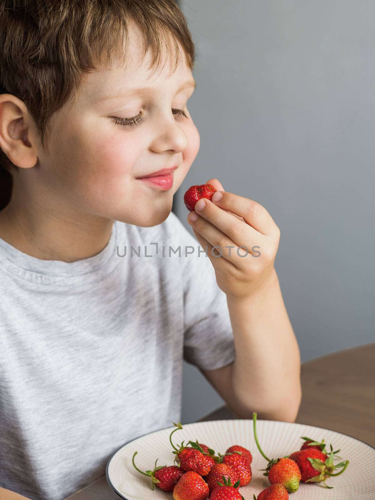 Little boy eats fresh organic strawberry with relish by fascinadora