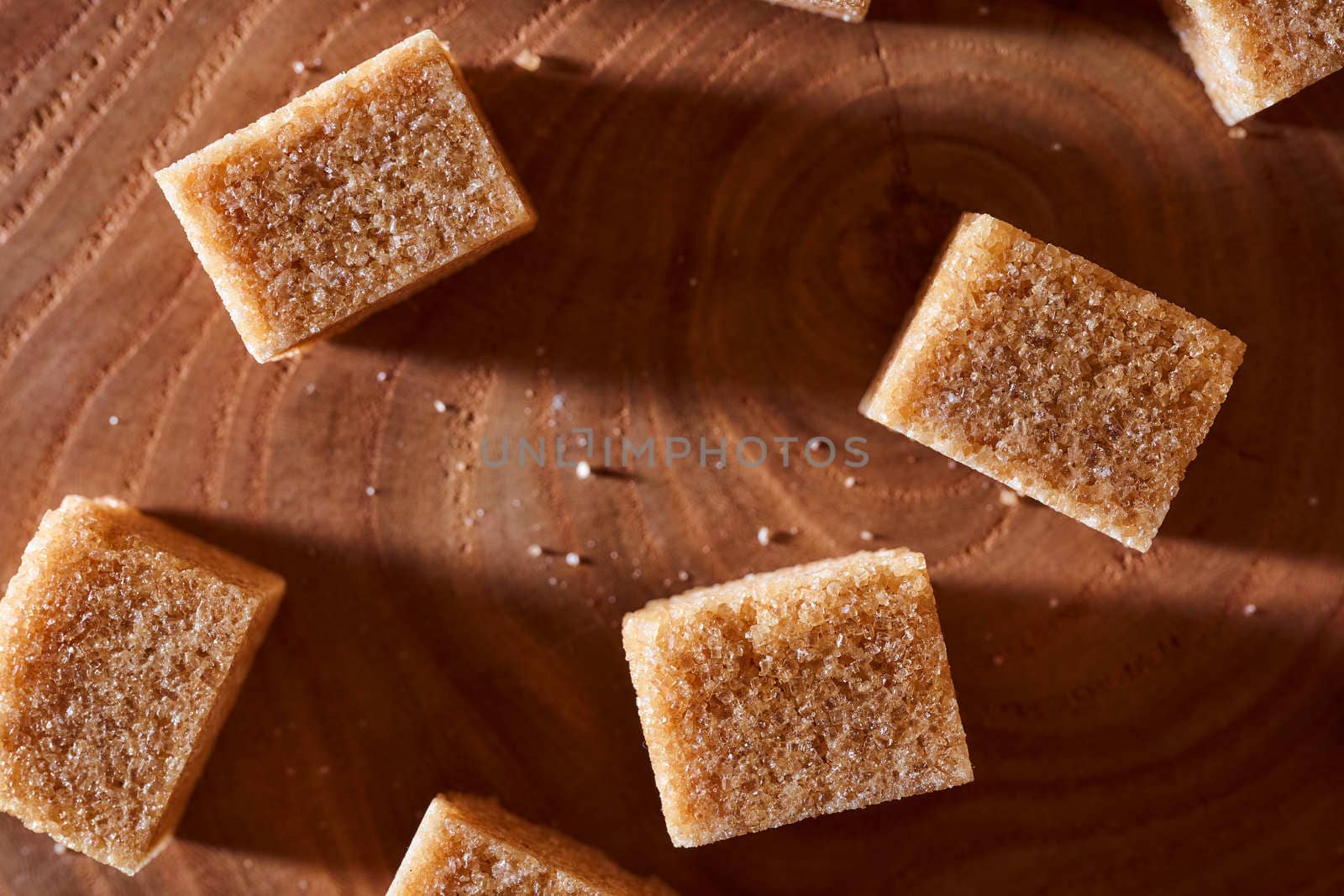 Brown cane sugar pieces on a slice, a plank of wood. High quality photo