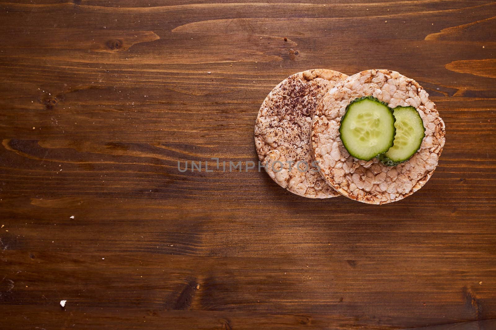 round buckwheat bread on which are two fresh cucumbers on a brown background. High quality photo