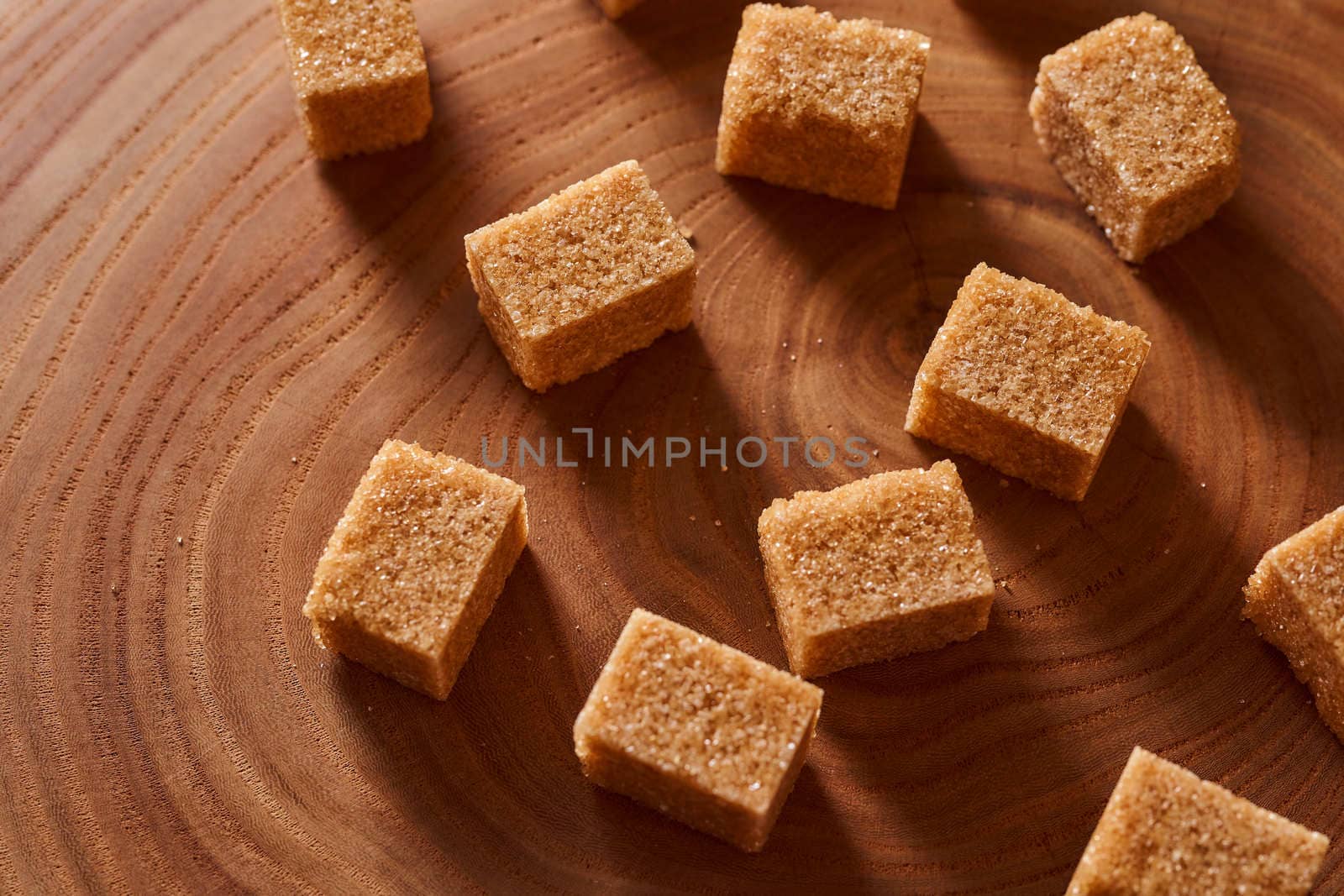 Brown cane sugar pieces on a slice, a plank of wood. High quality photo