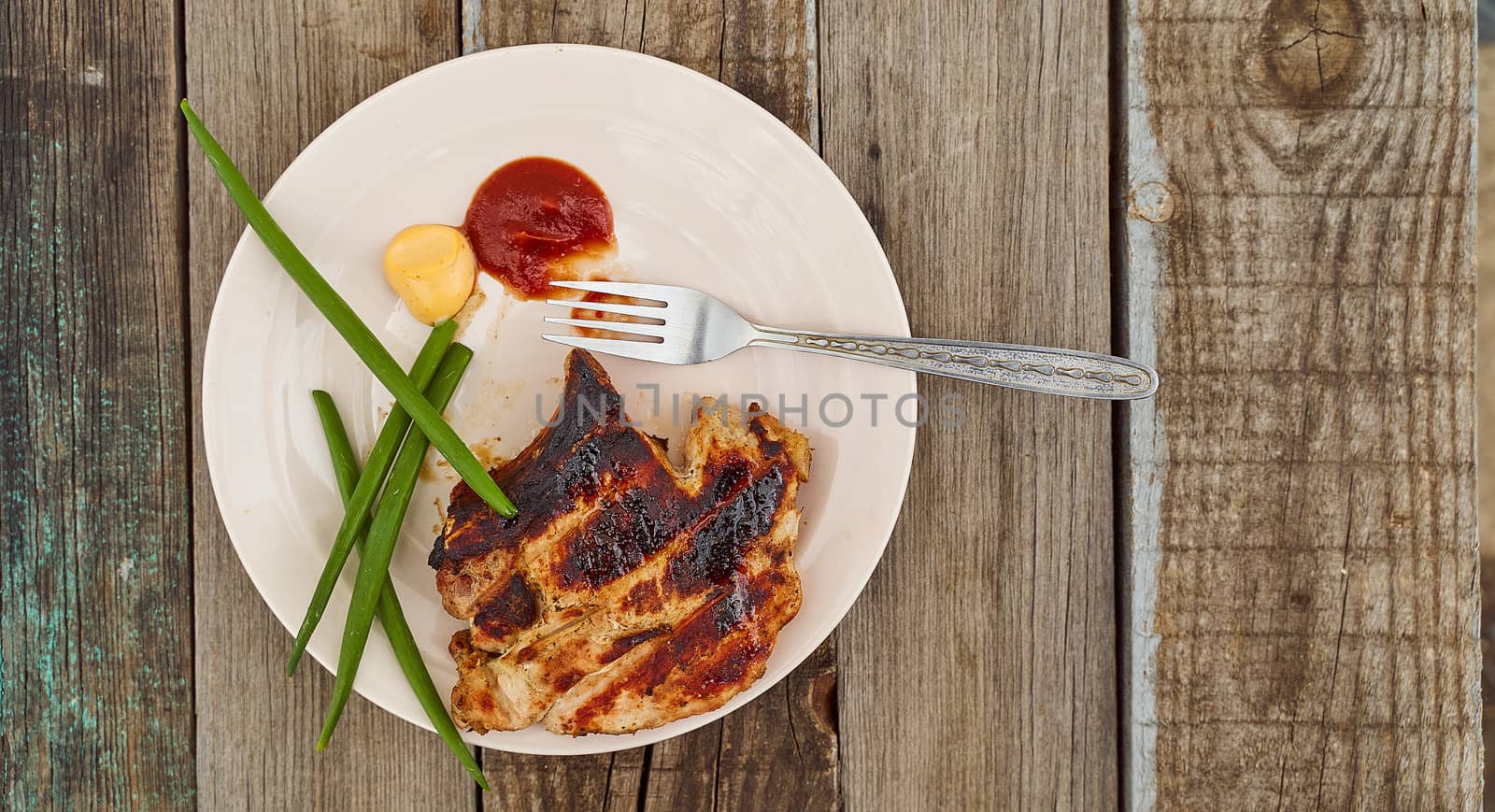 Ready pork steak in a white plate with green onions on an old wooden table. High quality photo