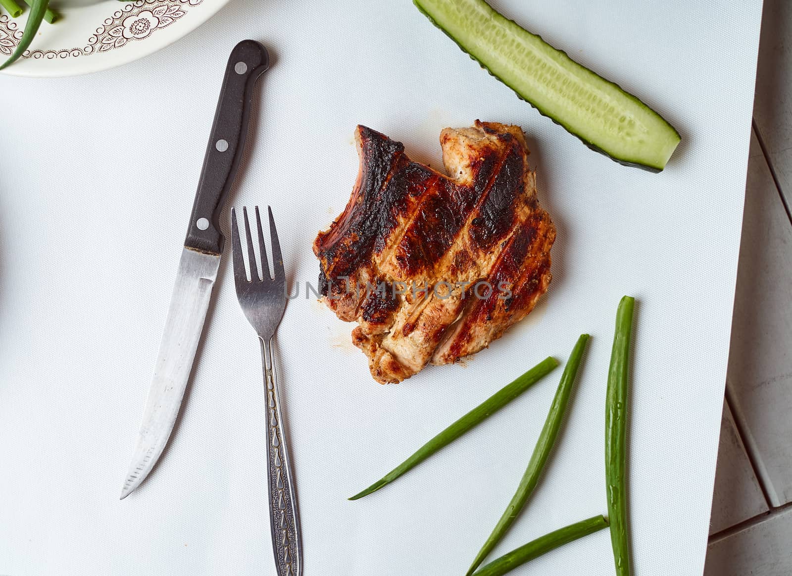 Ready pork steak in a white plate with green onions on a white plate. With copy space. High quality photo