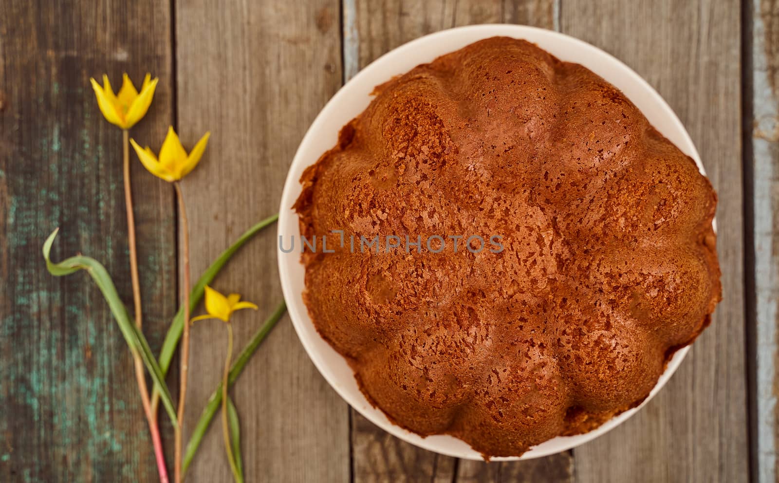 Homemade cupcake with chocolate filling inside on a wooden table with a Yellow Woodland tulips, Wild tulips on a wooden background. Close-up.. High quality photo