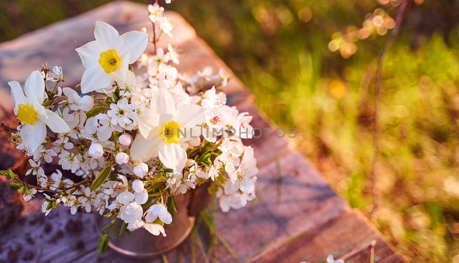 Steel kettle with sprigs of cherry blossoms, pears and apple trees on a natural blurred background. High quality photo