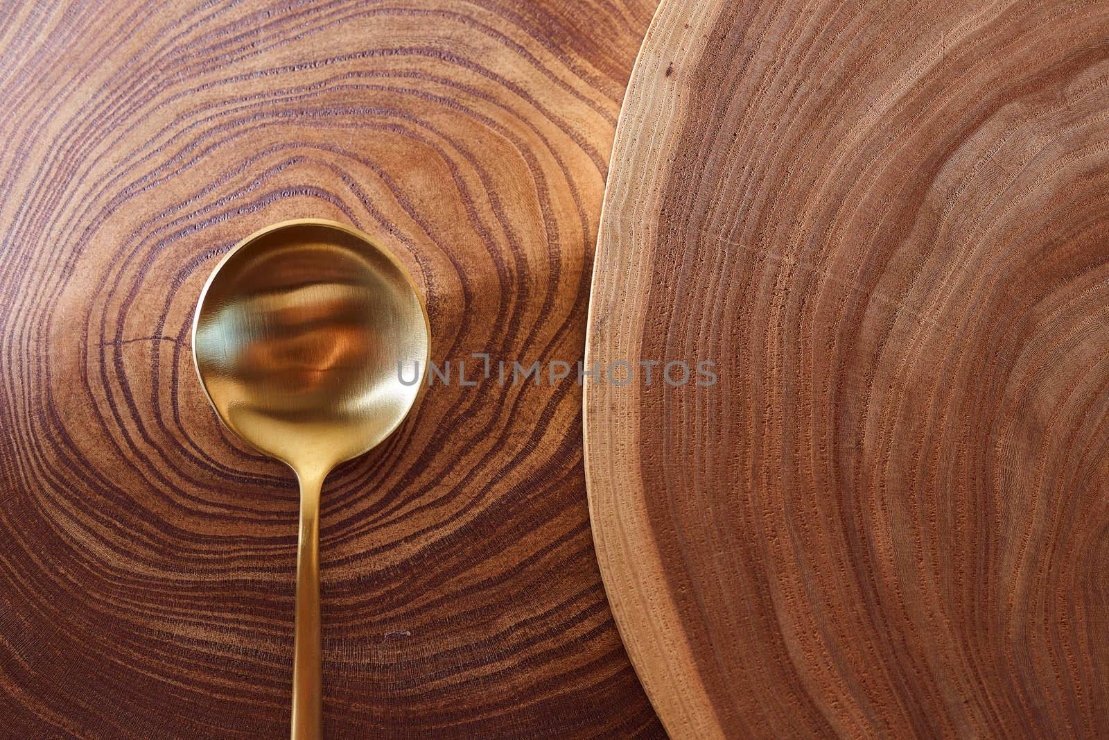 The golden spoon lies on a slice of a tree. wooden table. With copy space. High quality photo