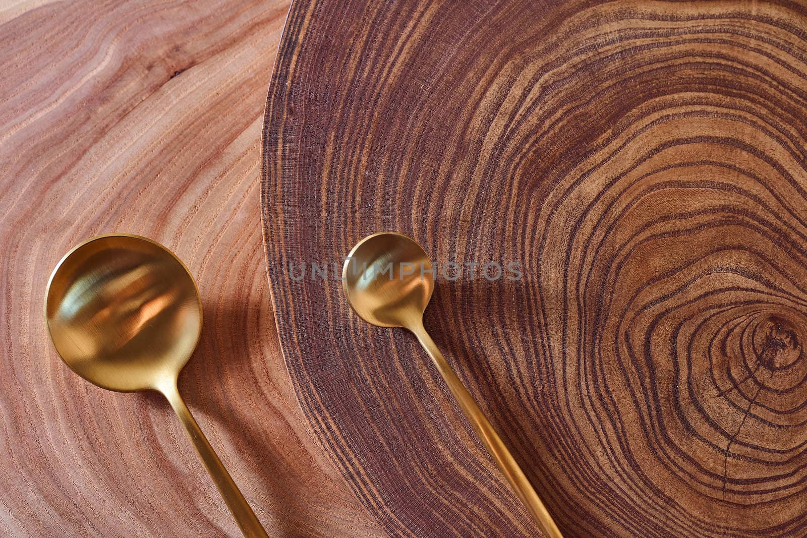 The golden spoon lies on a slice of a tree. wooden table. With copy space. High quality photo