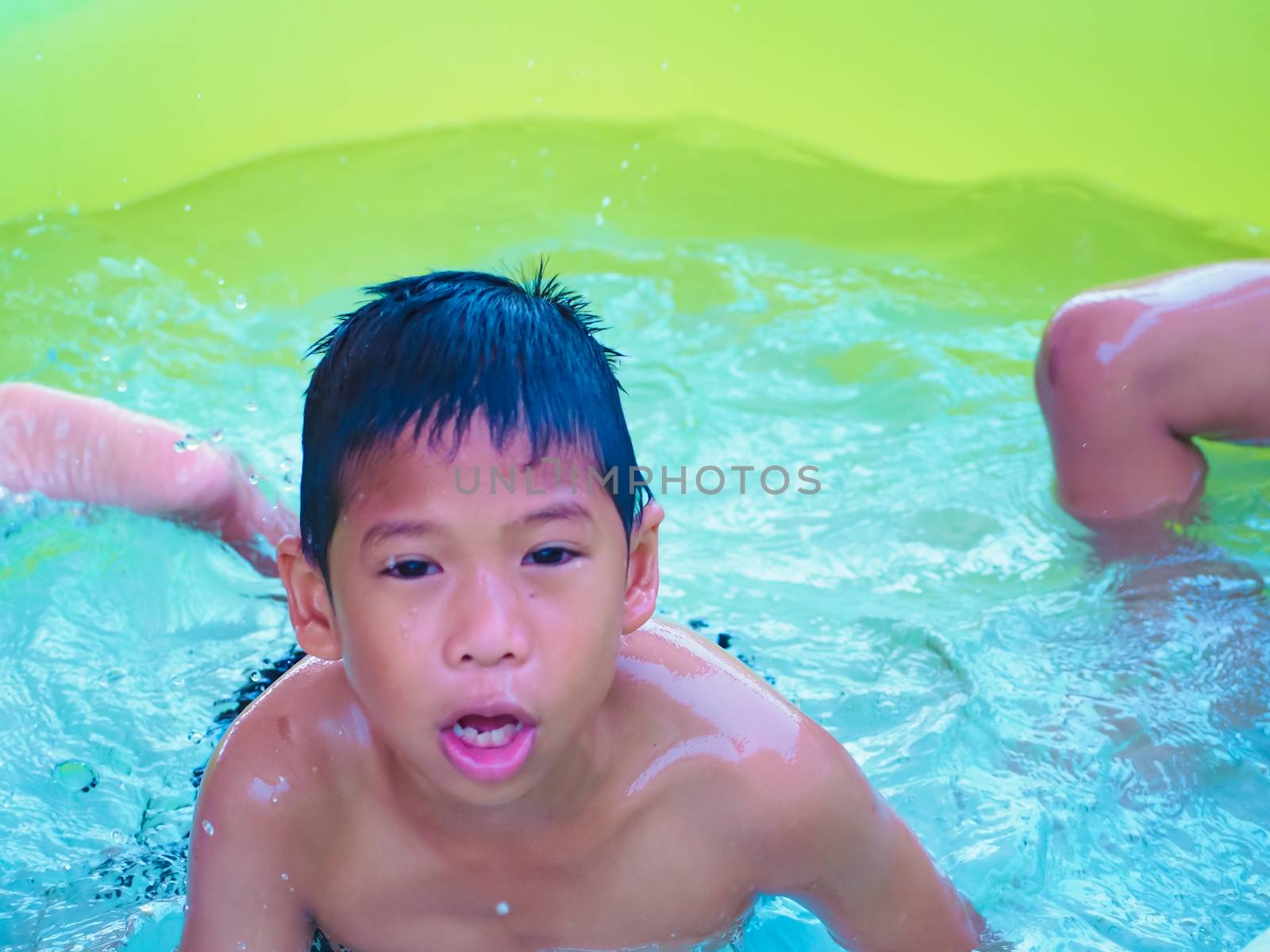 A boy playing in the pool and Smile happily. by Unimages2527