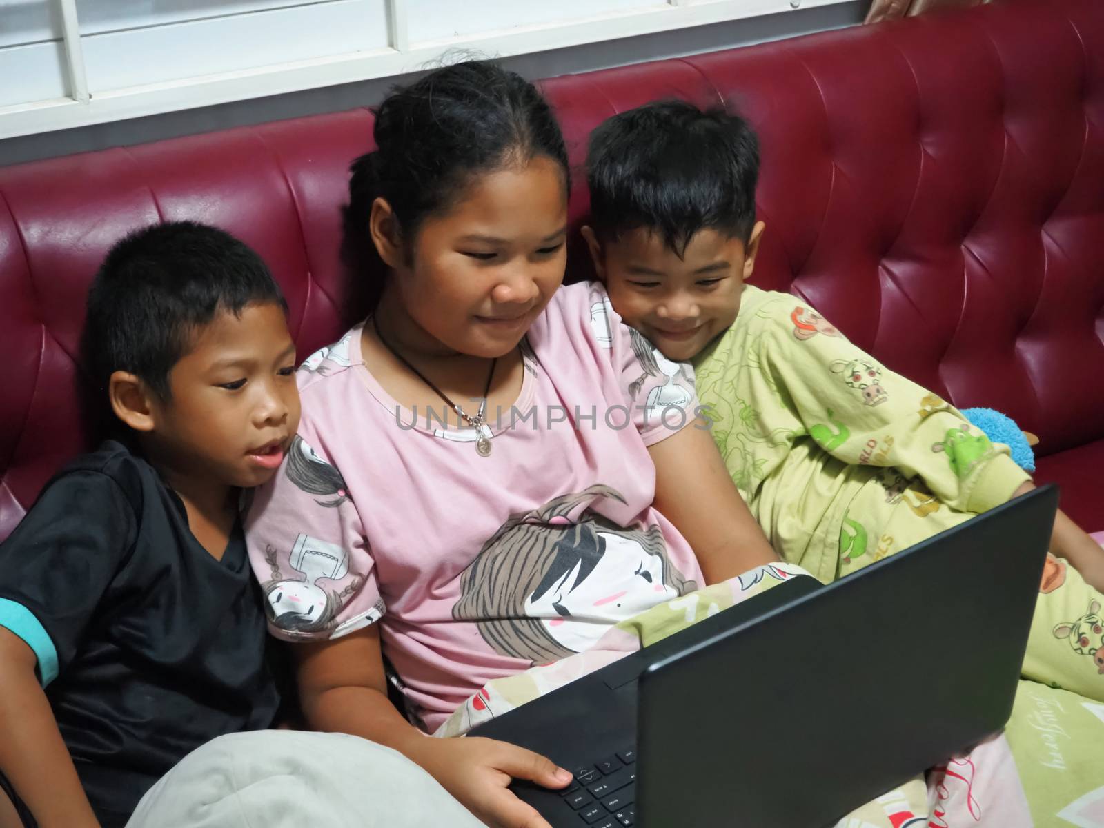 Boy and girl Sit happily watching a movie on your laptop on the by Unimages2527