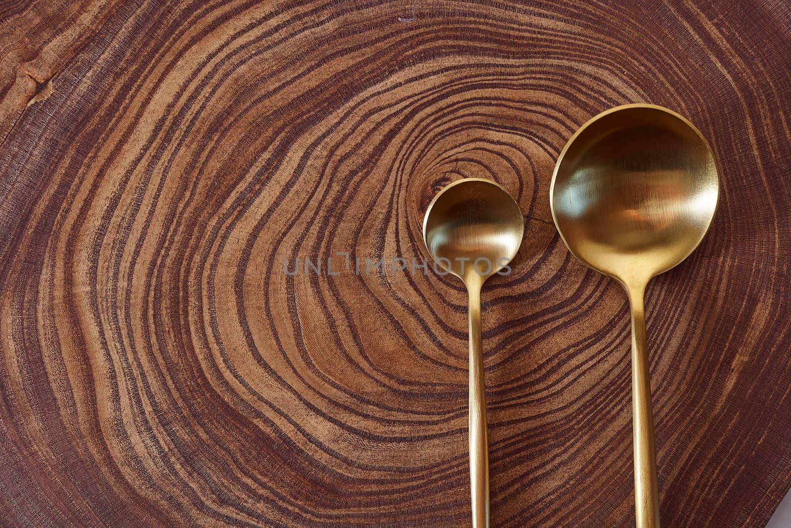 The golden spoons lies on a slice of a tree. wooden table. With copy space. High quality photo