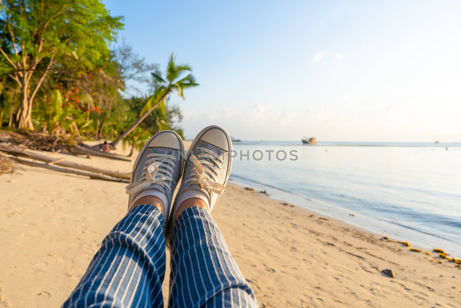 First-person view, a girl swinging on a swing on a sandy beach of a tropical island at sunset. Enjoys the vacation