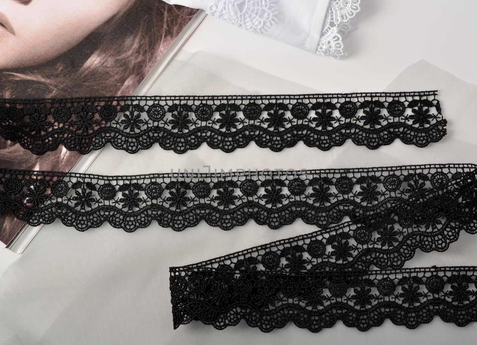 Tapes of black gentle guipure, beauty lace fabric on light background. Elastic material. Using for Atelier and needlework store.