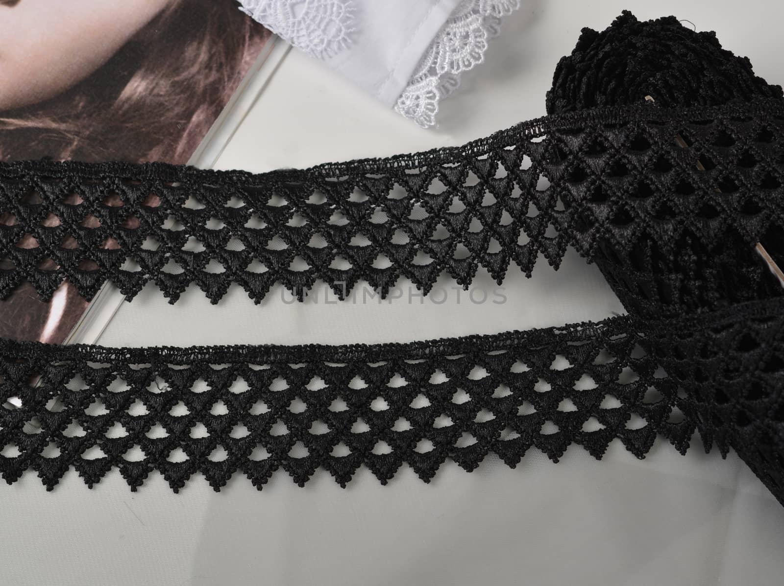 Tapes of black gentle guipure, beauty lace fabric on light background. Elastic material. Using for Atelier and needlework store.