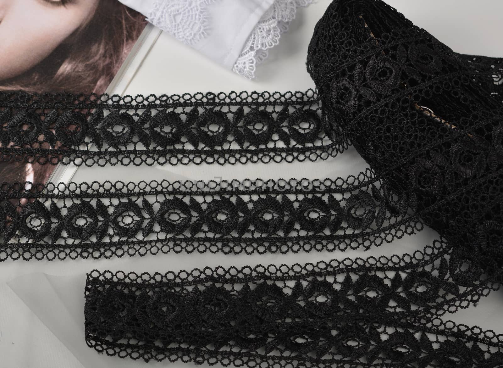 Tapes of black gentle guipure, beauty lace fabric on light background. Elastic material. Using for Atelier and needlework store.