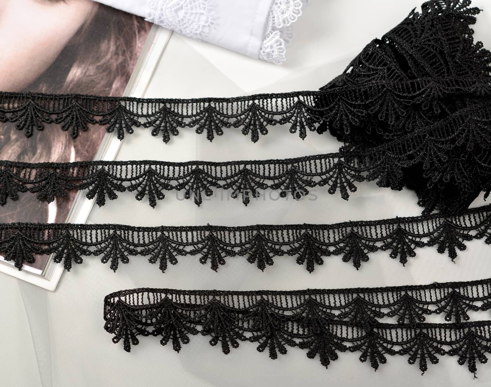 Tapes of black gentle guipure, beauty lace fabric on light background. Elastic material. Using for Atelier and needlework store.