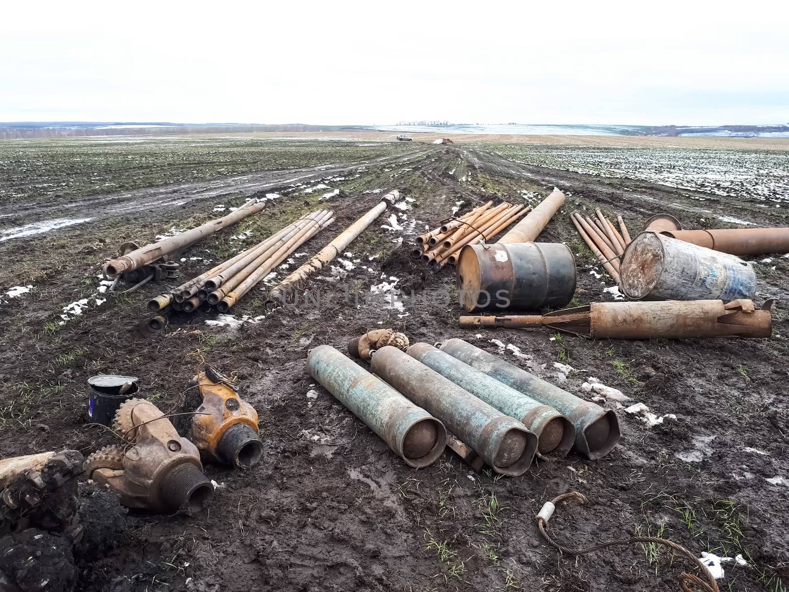 Metal left over from the drilling of a well in the tundra. Barrels, cylinders and chisel balls