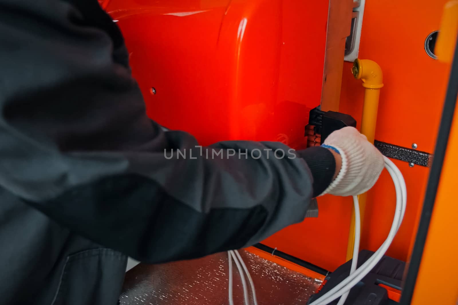 Repair work in the electric flap. The electrician handles the equipment in the electric flap with his hand in the glove.