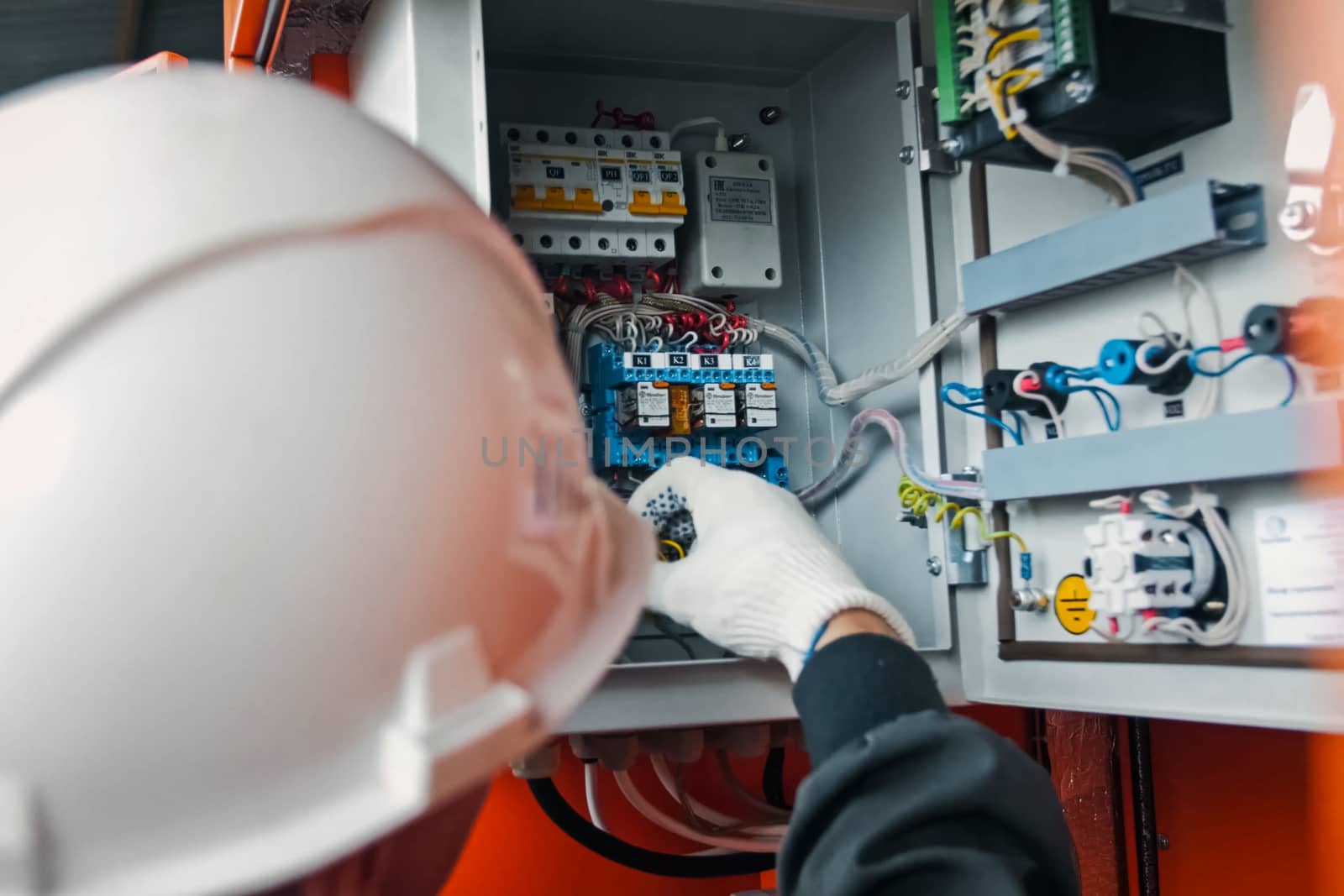 Repair work in the electric flap. The electrician handles the equipment in the electric flap with his hand in the glove.