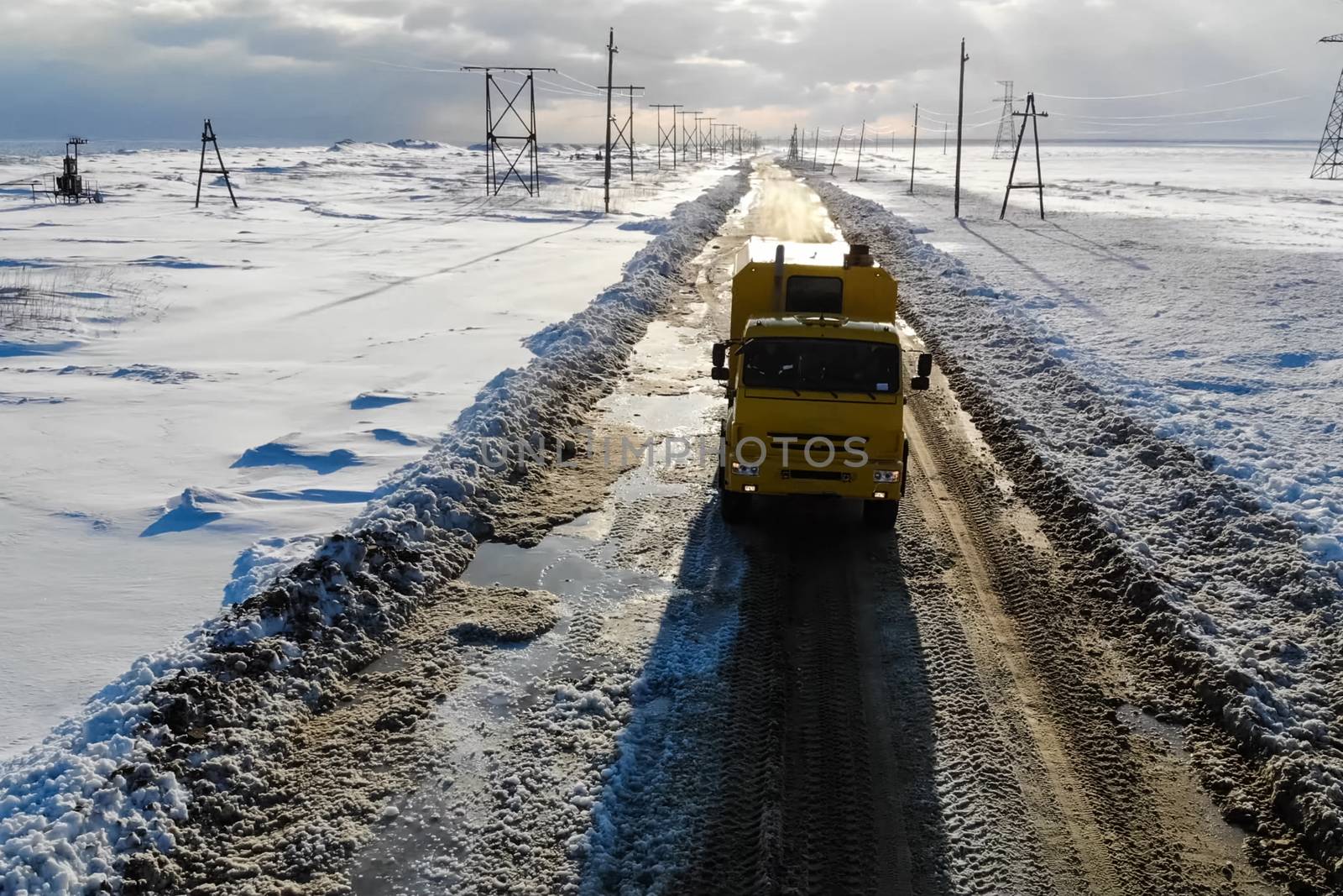 The truck rides on a winter road among the snow.