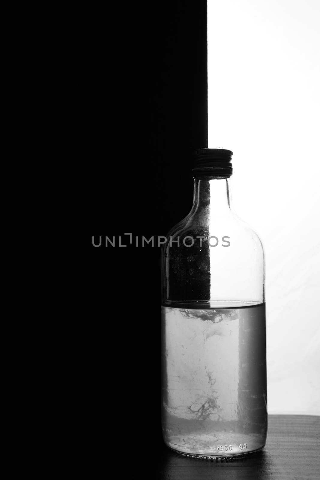 A small bottle on a black and white background. Half black and half white. High quality photo