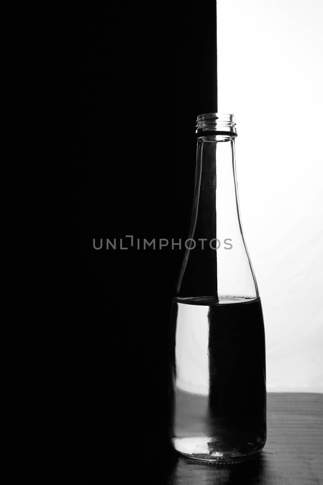 A bottle of water on a black and white background. Optical over-reflection effect. High quality photo