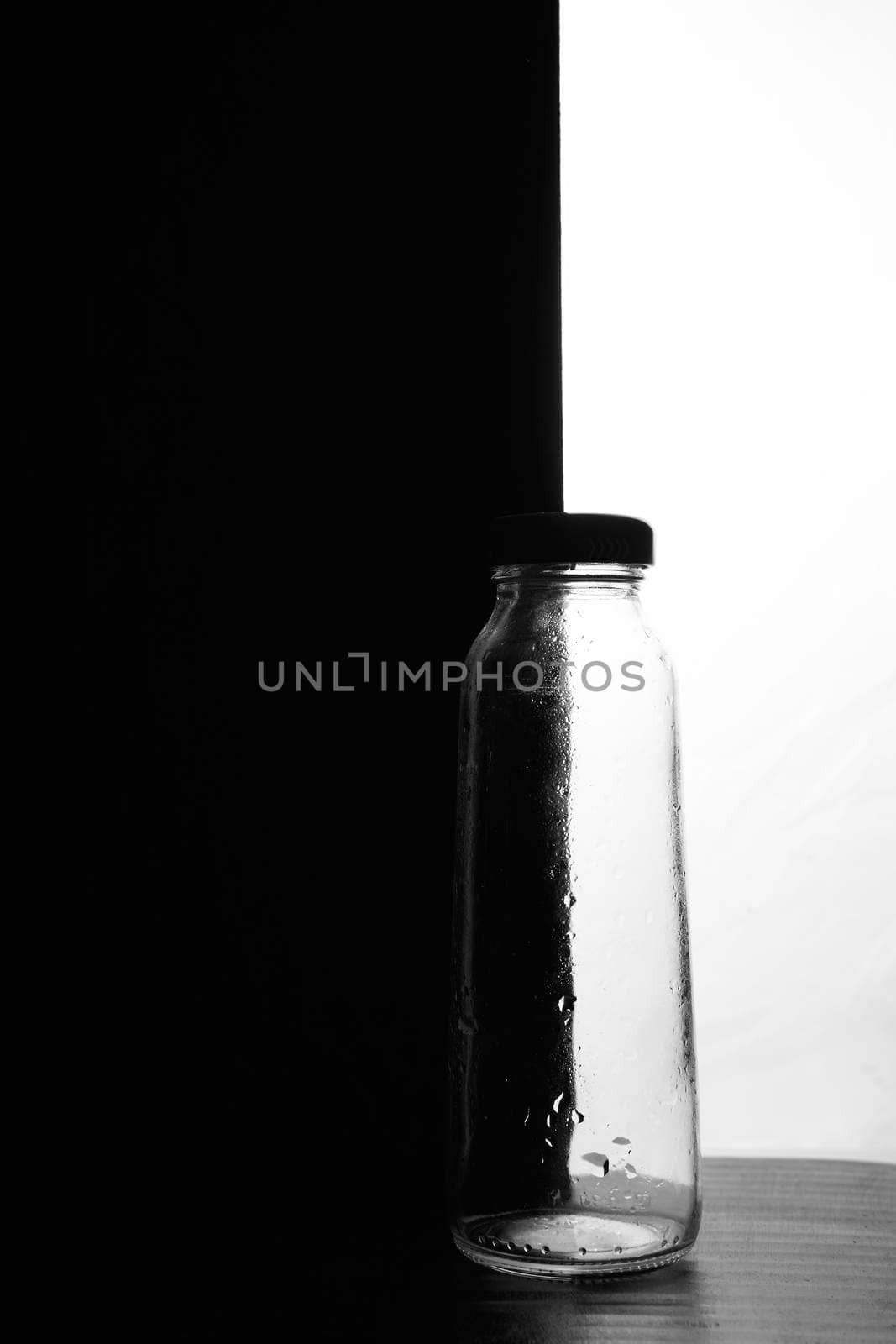 A small bottle on a black and white background. Half black and half white. High quality photo