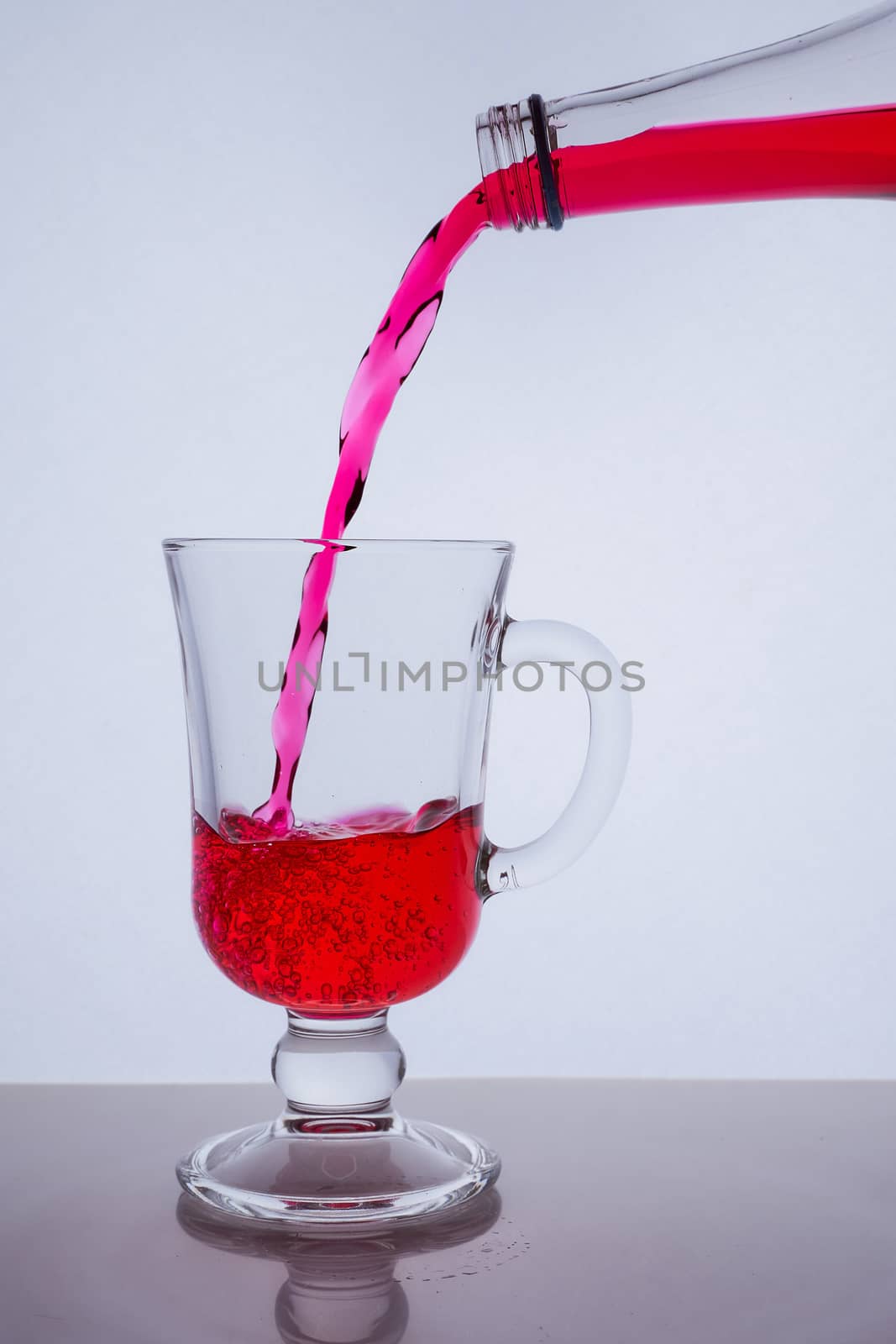 red liquid poured into a glass glass on a white background with bubbles. Hight quality photo