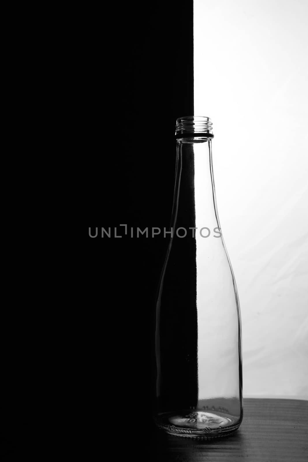 A small bottle on a black and white background. Half black and half white. High quality photo