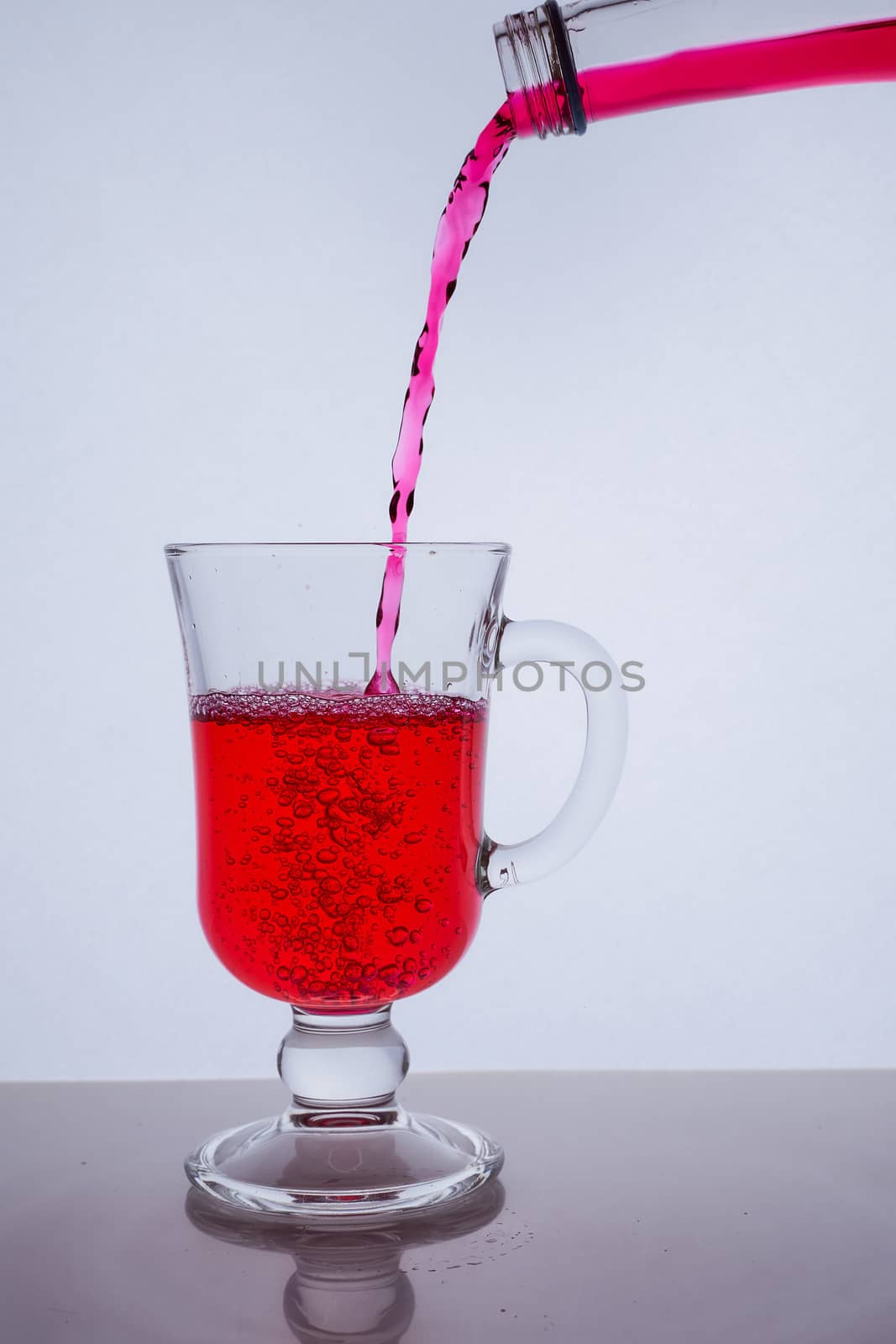 red liquid poured into a glass glass on a white background with bubbles. Hight quality photo