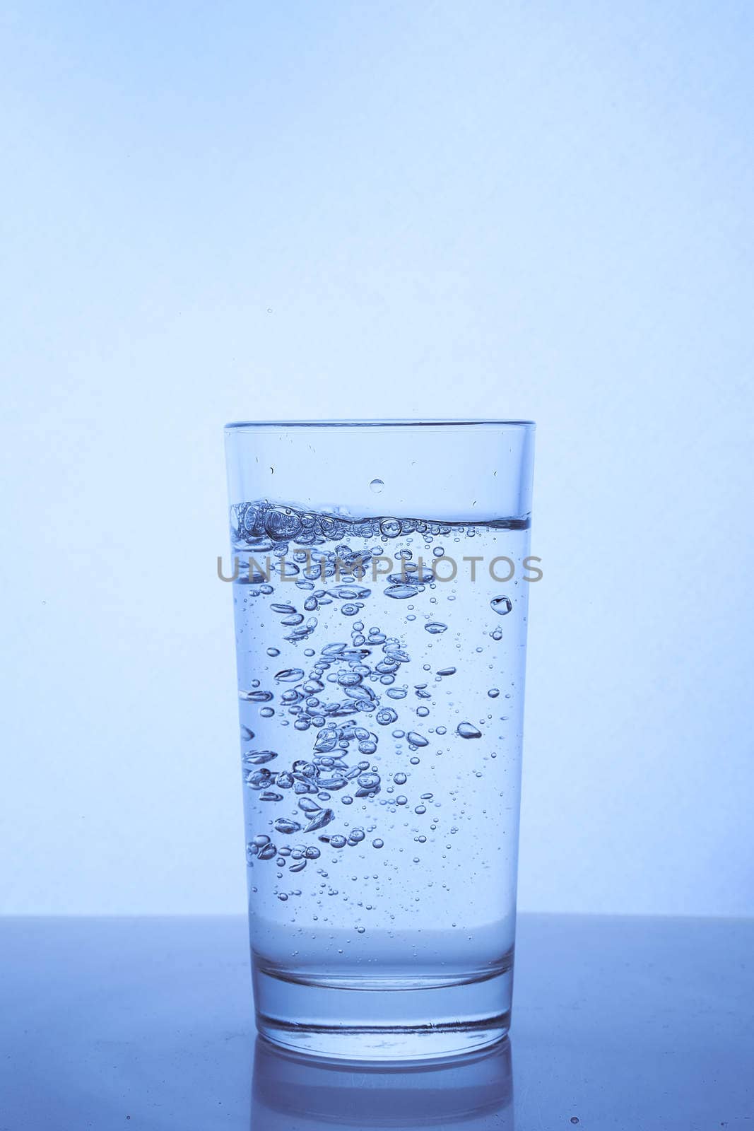 fresh clean water is poured from a bottle into a glass cup. Light background.. Hight quality photo