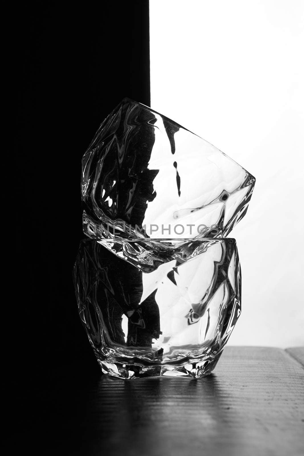 glasses of whiskey lie on top of each other. There's a bottle of whiskey. Black white background. Silhouettes. High quality photo