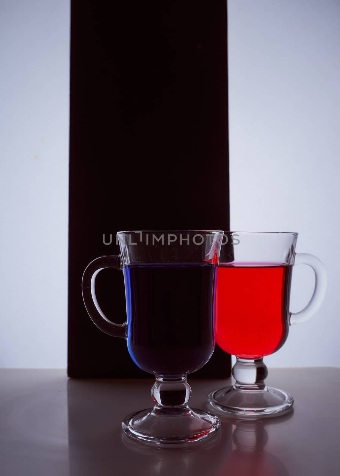 silhouettes of two glasses on a black and white background. Blue and red liquid. Hight quality photo