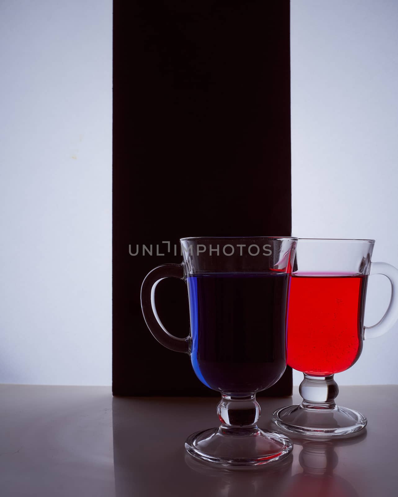 silhouettes of two glasses on a black and white background. Blue and red liquid. Hight quality photo