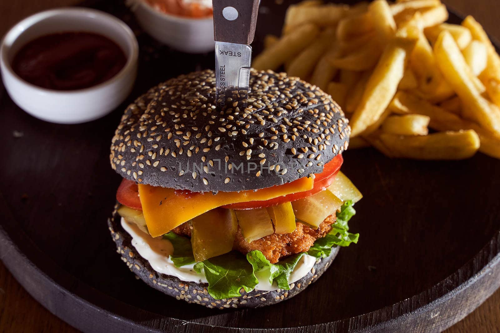 Black burger with sesame seeds with fries and salad of cabbage closeup photo