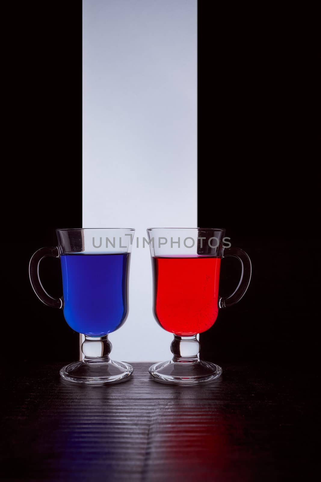 silhouettes of two glasses on a black and white background. Blue and red liquid. Hight quality photo