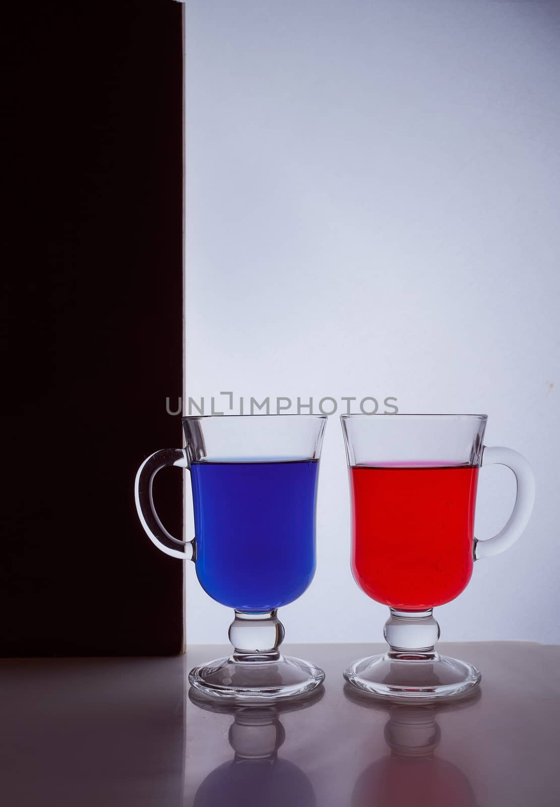 silhouettes of two glasses on a black and white background. Blue and red liquid. Hight quality photo