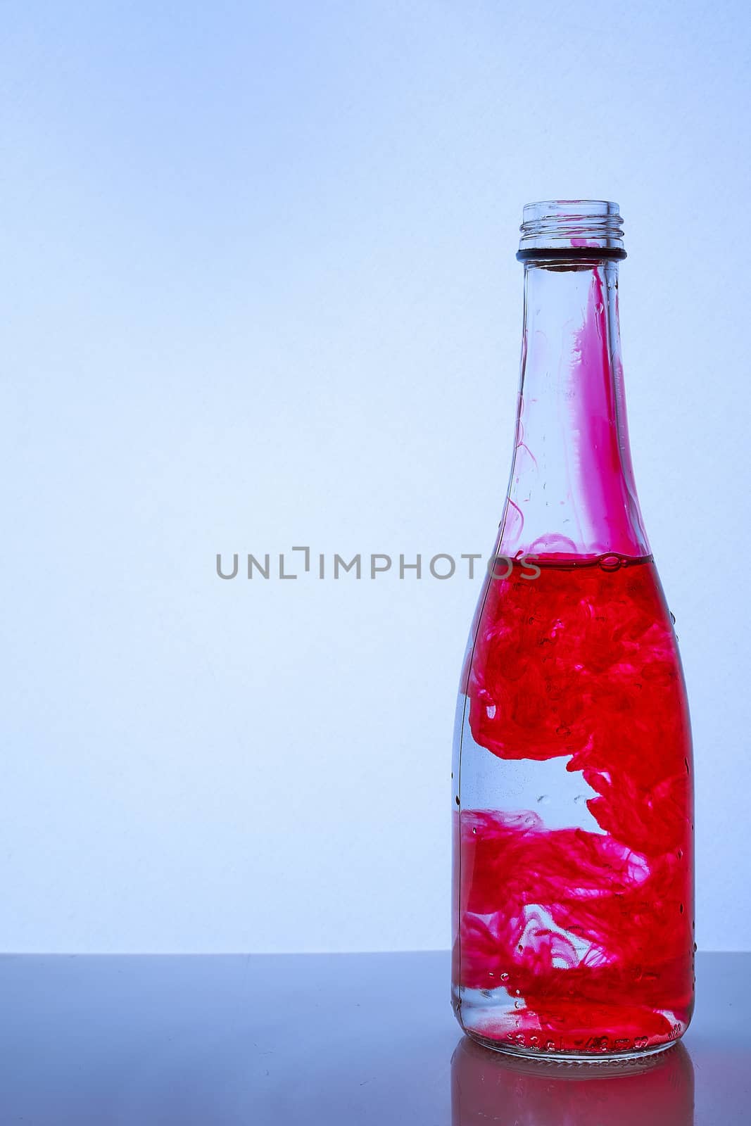 red ink mixed with water in a glass bottle on a light background. Hight quality photo