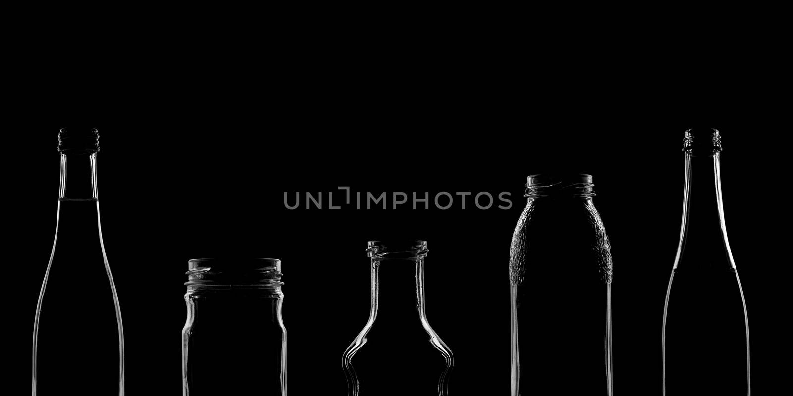 The silhouettes of bottles with various beautiful shapes on a black background. Banner for advertising with a place to insert text. High quality photo