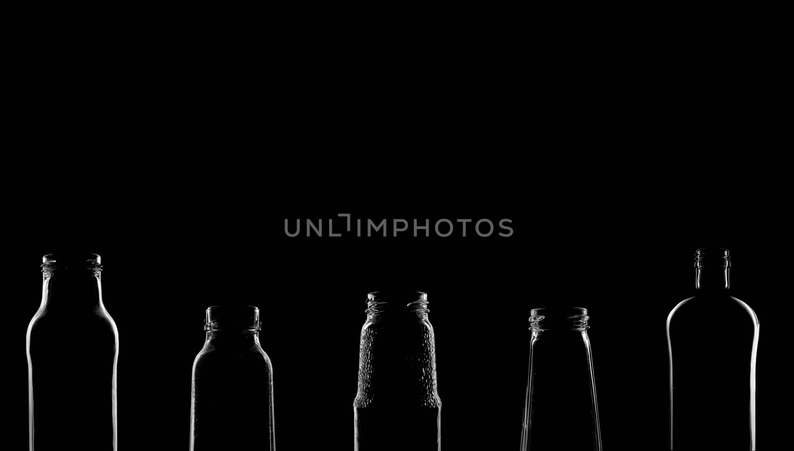 The silhouettes of bottles with various beautiful shapes on a black background. Banner for advertising with a place to insert text. High quality photo