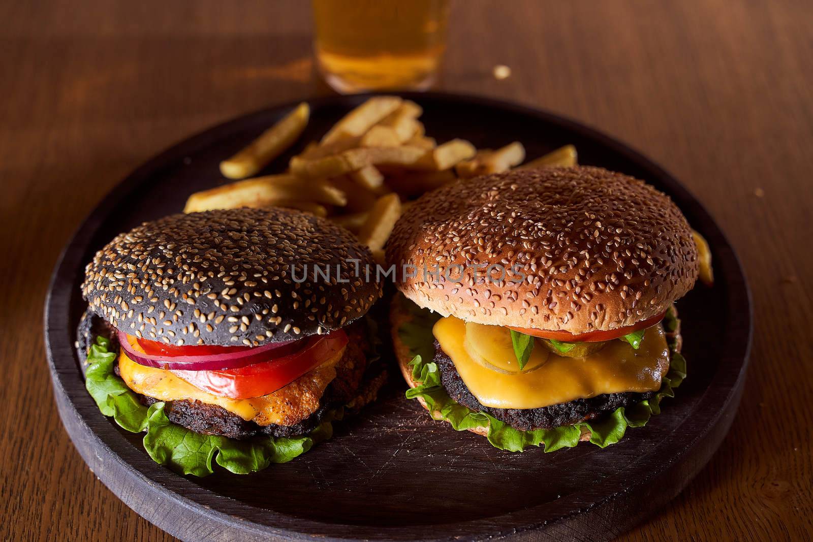 Two burgers dark and light leat on a wooden tray closeup photo