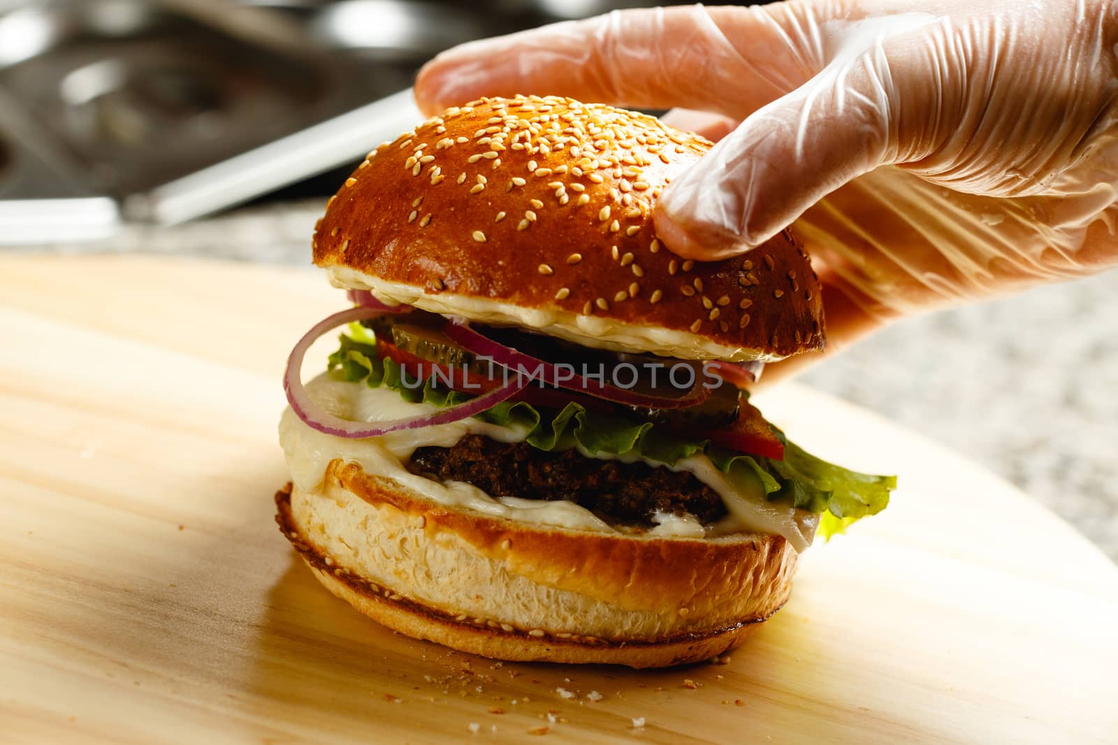 The woman's hand makes the finishing touch. Puts the bun on the burger closeup photo