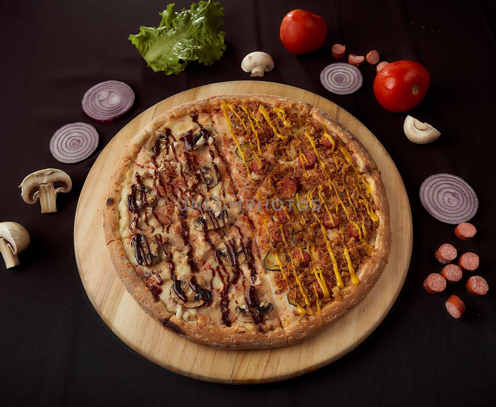 The finished pizza rests on a wooden tray with ingredients. black background top view photo