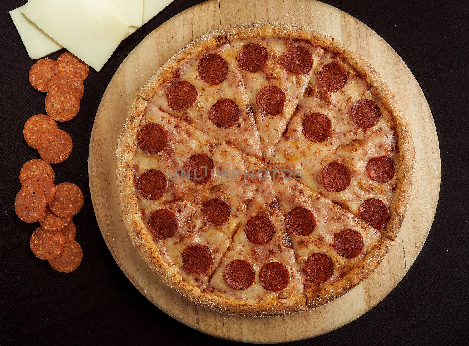 Large pepperoni pizza with ingredients on a black top view background top view photo