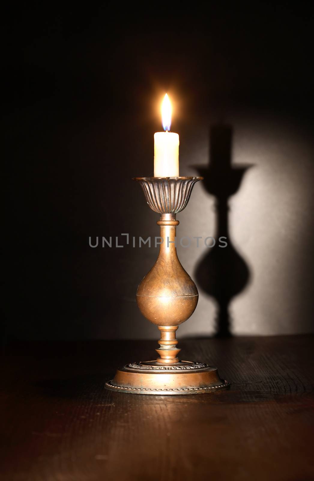 Elegant brass candlestick with lighting candle on dark background