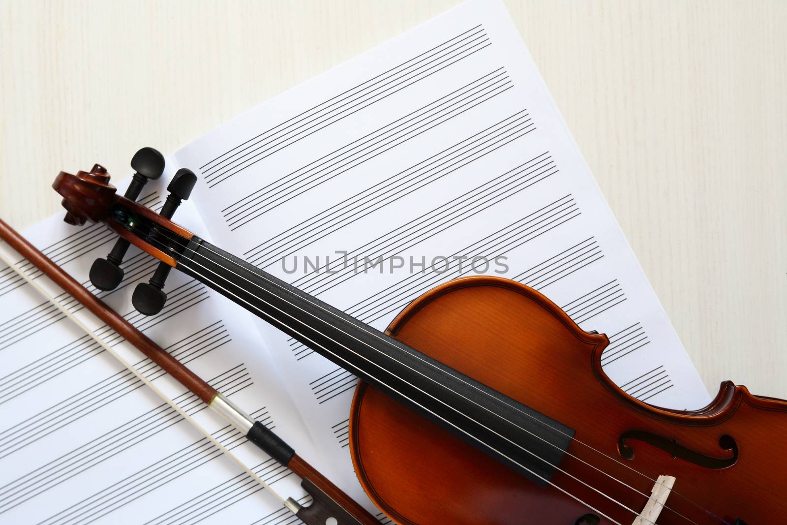 Nice violin and open blank music book on white wooden background
