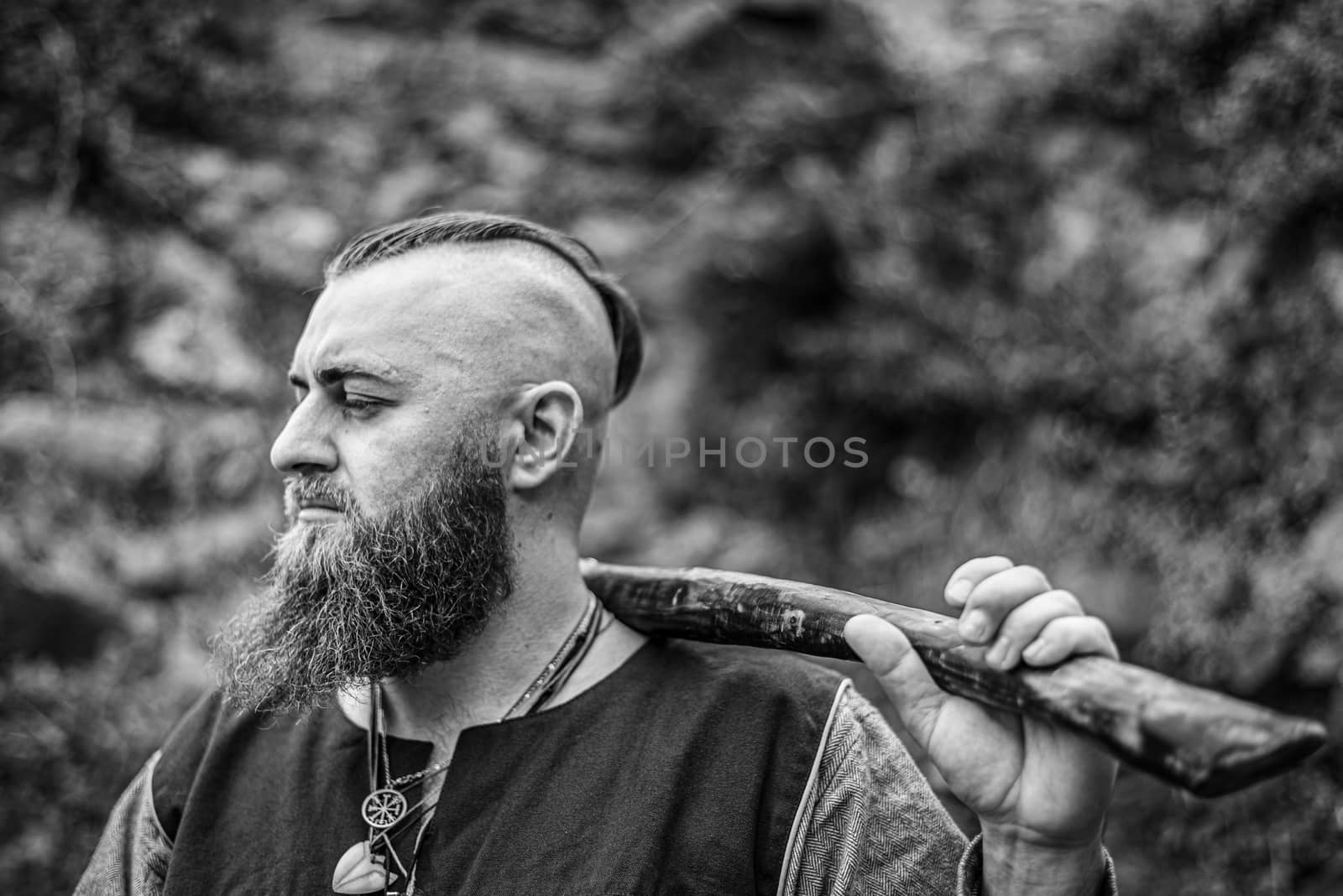 Viking portrait with thick beard, black and white image of historical re-enactment among medieval ruins