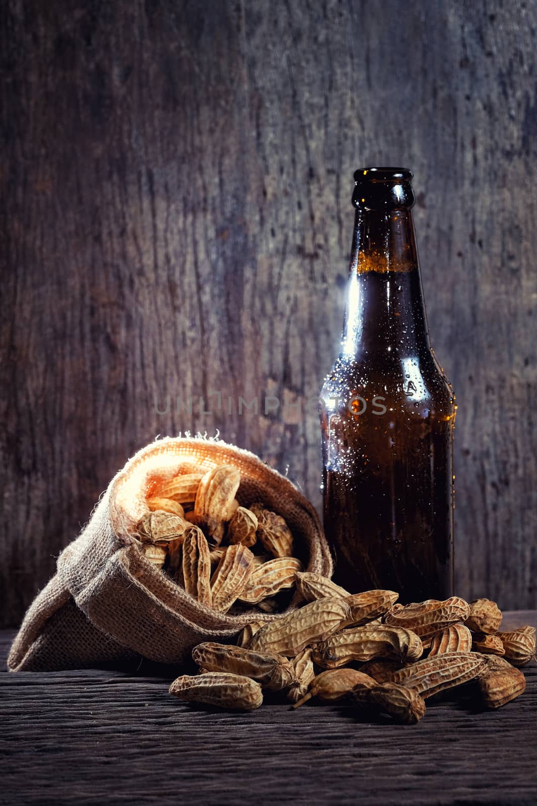 Peanuts and Beer bottle in wood background
 by Surasak